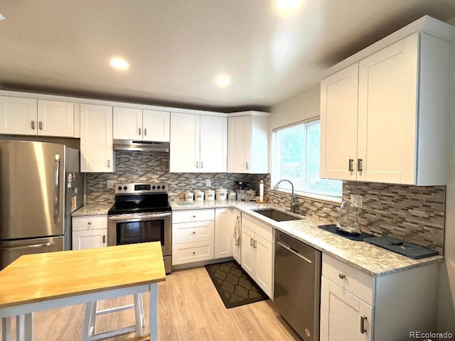 2285 S Knox Ct, Denver, CO 80219 - kitchen featuring stainless steel appliances, under cabinet range hood, light wood-style flooring, white cabinets, and recessed lighting