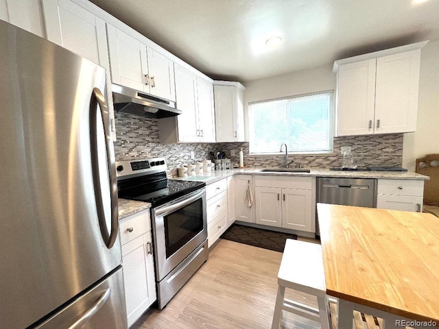 2285 S Knox Ct, Denver, CO 80219 - kitchen with stainless steel appliances, under cabinet range hood, tasteful backsplash, and white cabinets