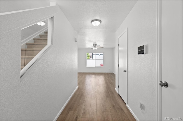 19817 E 47th Pl, Denver, CO 80249 - hallway with baseboards, a textured wall, wood finished floors, a textured ceiling, and stairs