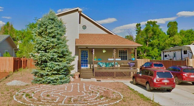 bungalow-style home with a porch, a shingled roof, and fence