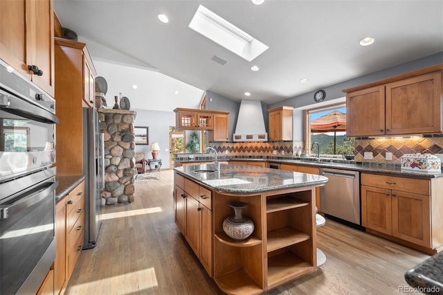 kitchen with decorative backsplash, appliances with stainless steel finishes, open shelves, light wood-type flooring, and a sink