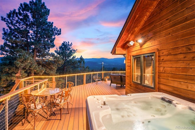 deck at dusk featuring a mountain view and hot tub deck surround