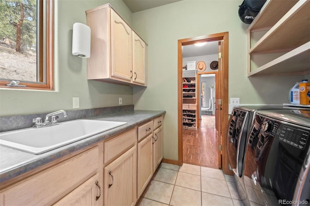 washroom featuring a sink, cabinet space, light tile patterned floors, and washing machine and clothes dryer