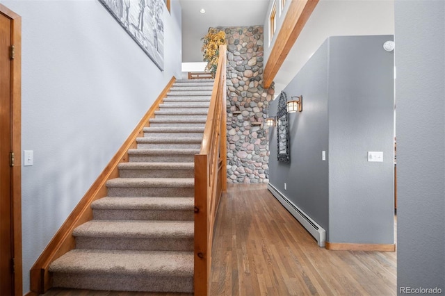 staircase featuring baseboards, a baseboard radiator, and wood finished floors