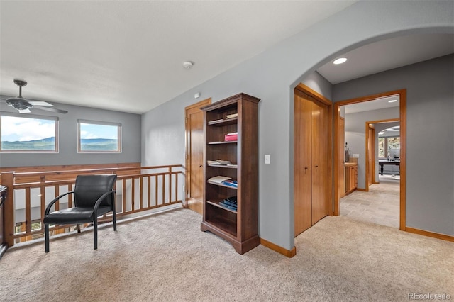 home office with arched walkways, ceiling fan, light carpet, and baseboards