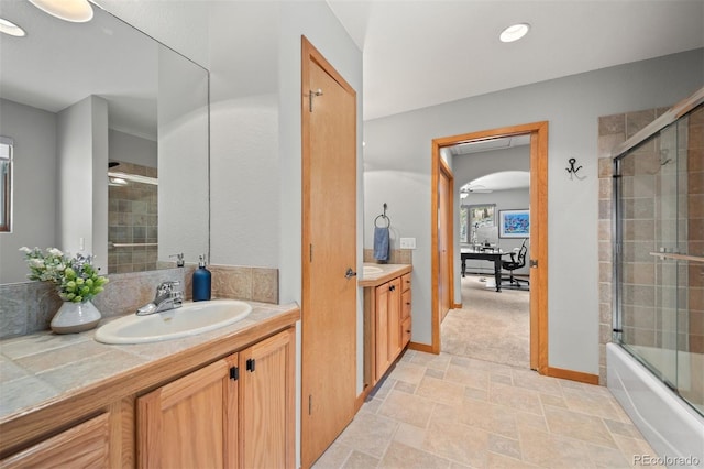 full bath featuring stone finish floor, vanity, baseboards, combined bath / shower with glass door, and recessed lighting