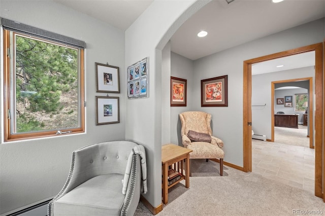 sitting room with arched walkways, baseboards, a baseboard radiator, light carpet, and recessed lighting