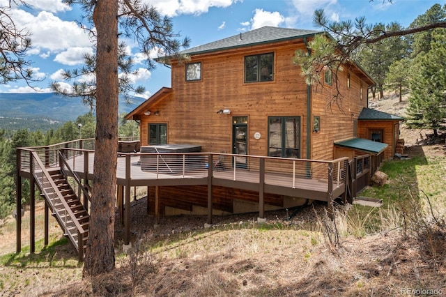 back of house featuring stairway, a wooden deck, and roof with shingles