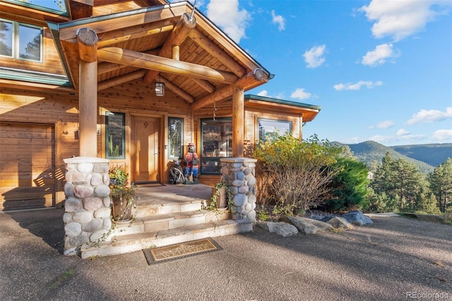 view of exterior entry with a porch, a garage, and a mountain view