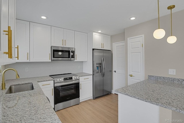 kitchen with stainless steel appliances, sink, decorative light fixtures, light hardwood / wood-style floors, and white cabinetry