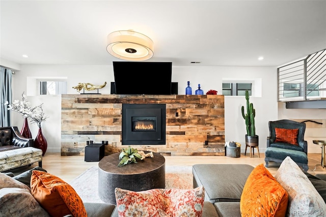 living room featuring wood finished floors, a glass covered fireplace, and recessed lighting