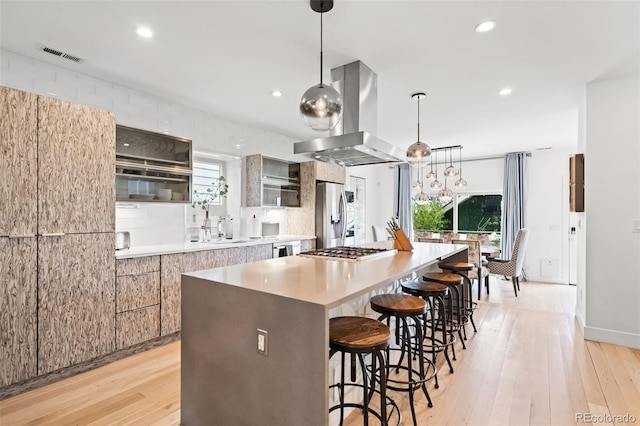 kitchen with island range hood, a large island, stainless steel appliances, a kitchen bar, and visible vents