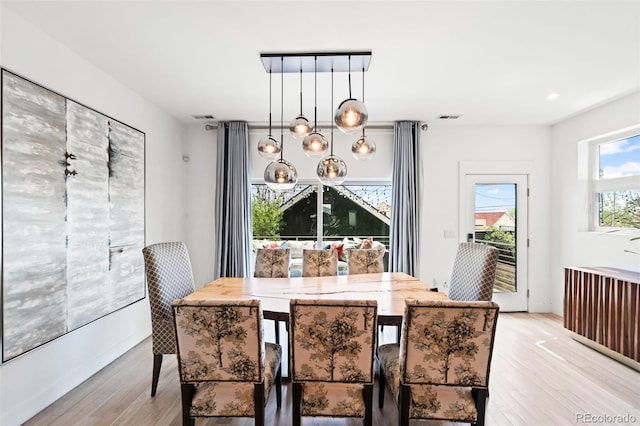dining room with light wood-type flooring, baseboards, visible vents, and a chandelier