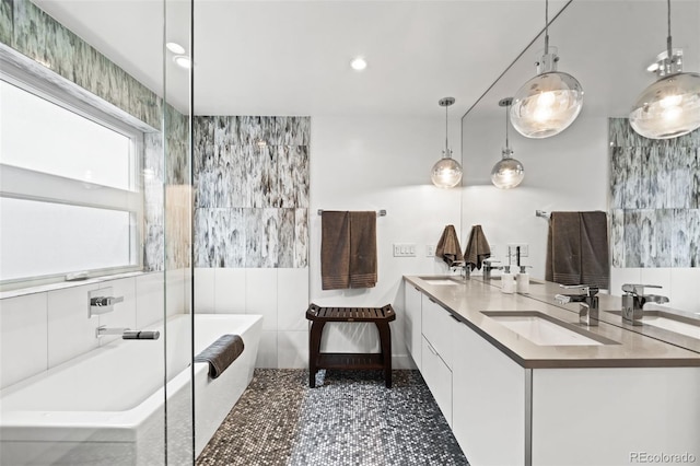 bathroom with a freestanding bath, a sink, double vanity, and recessed lighting
