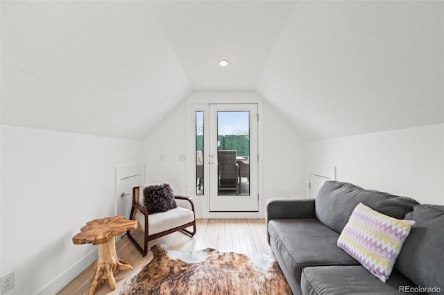 living area with light wood-type flooring, lofted ceiling, and baseboards