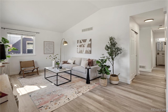 living room with light wood-type flooring and vaulted ceiling