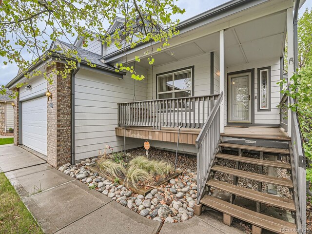 property entrance with covered porch, an attached garage, and concrete driveway