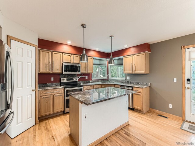 kitchen with stainless steel appliances, light wood-type flooring, dark stone countertops, a sink, and recessed lighting