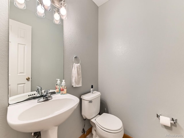 half bath featuring a sink, toilet, and a chandelier