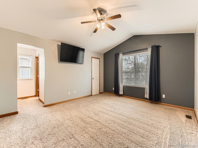 carpeted spare room featuring ceiling fan, baseboards, and vaulted ceiling