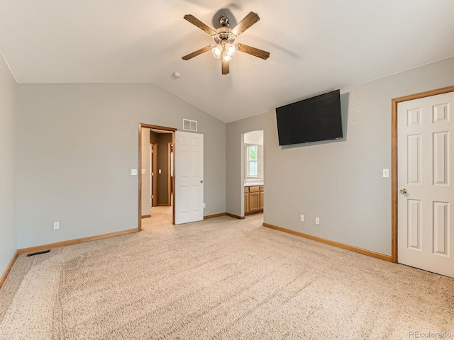 unfurnished bedroom featuring baseboards, vaulted ceiling, light carpet, ceiling fan, and ensuite bath