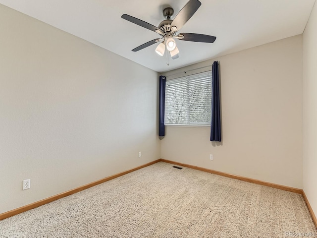 empty room with carpet flooring, a ceiling fan, and baseboards