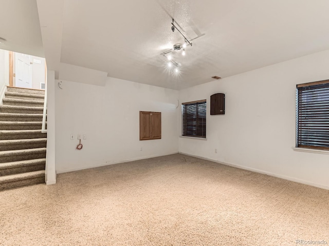 below grade area with stairs, rail lighting, and baseboards