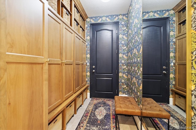 mudroom with wallpapered walls and light tile patterned floors