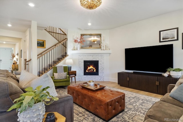 living area featuring recessed lighting, stairs, a glass covered fireplace, and wood finished floors