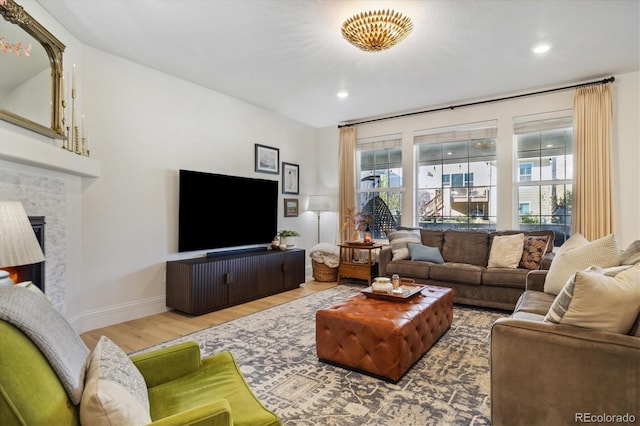 living room with recessed lighting, baseboards, wood finished floors, and a lit fireplace