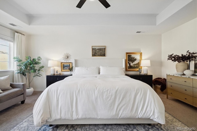 bedroom with ceiling fan, carpet, a tray ceiling, and visible vents