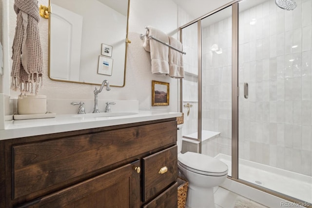 full bathroom featuring vanity, a shower stall, and toilet