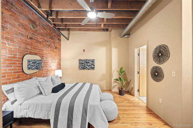 bedroom with a ceiling fan, wood finished floors, brick wall, a towering ceiling, and beamed ceiling