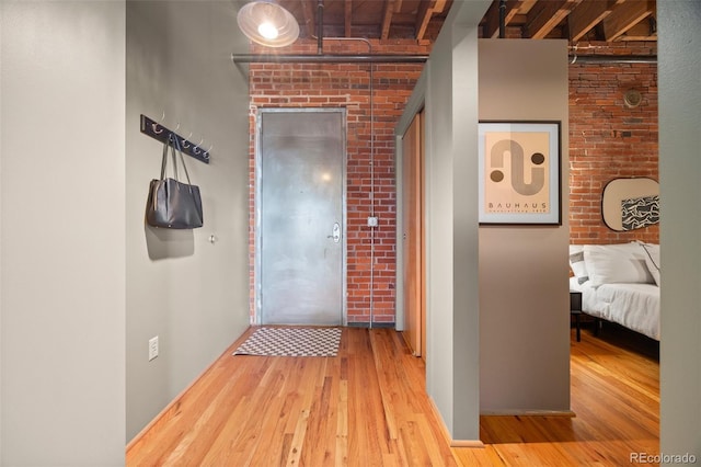 hall featuring brick wall, baseboards, and wood finished floors