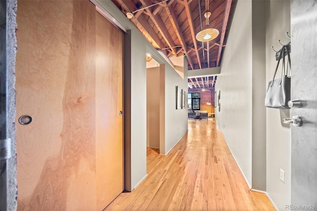 hall with light wood finished floors, beamed ceiling, wooden ceiling, and baseboards