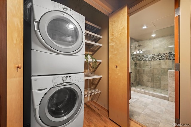 washroom featuring laundry area, wood finished floors, and stacked washer and clothes dryer