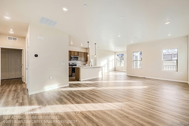 unfurnished living room with visible vents, recessed lighting, light wood-type flooring, and baseboards