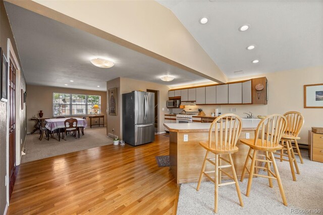 3176 S Alton Ct, Denver, CO 80231 - kitchen with stainless steel appliances, a peninsula, light countertops, light wood finished floors, and a breakfast bar area