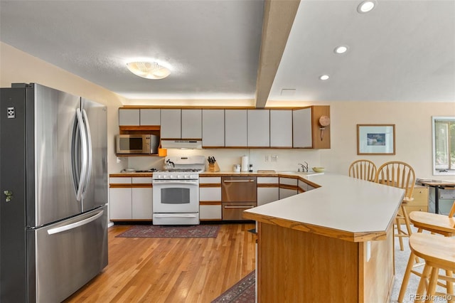 3176 S Alton Ct, Denver, CO 80231 - kitchen featuring stainless steel appliances, a peninsula, light wood-type flooring, under cabinet range hood, and light countertops