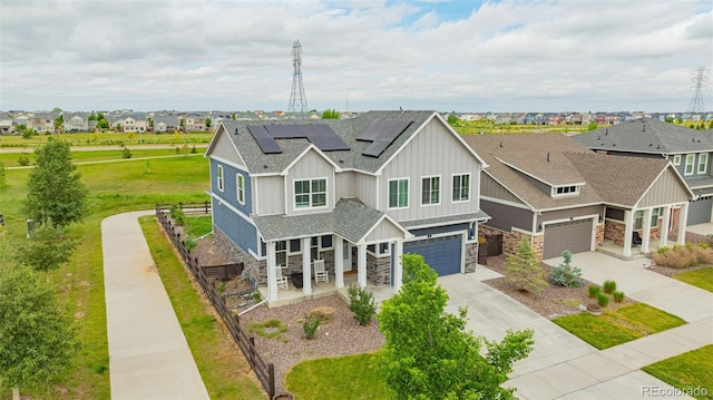 91 S Quantock St, Aurora, CO 80018 - view of front of home with stone siding, driveway, roof mounted solar panels, and a garage