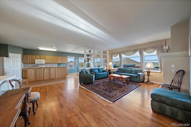 living area with plenty of natural light, light wood-type flooring, and baseboards