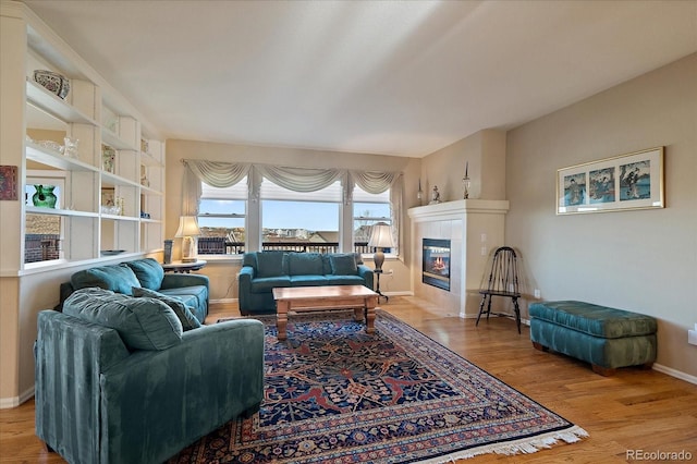 living area with a tile fireplace, baseboards, and wood finished floors