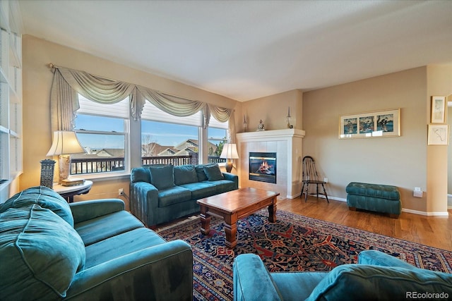 living area with baseboards, wood finished floors, and a tile fireplace