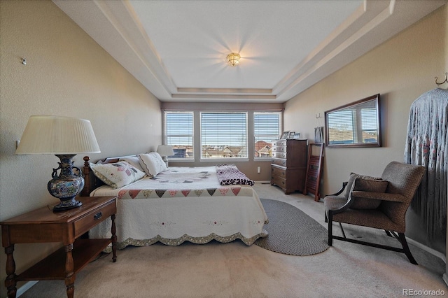 bedroom with light colored carpet and a tray ceiling