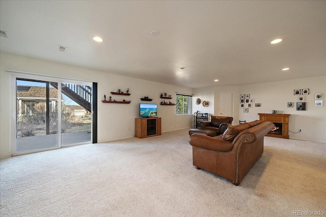 living room featuring light carpet, visible vents, recessed lighting, and a warm lit fireplace