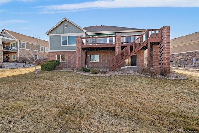 rear view of house with a lawn, a deck, board and batten siding, brick siding, and stairs