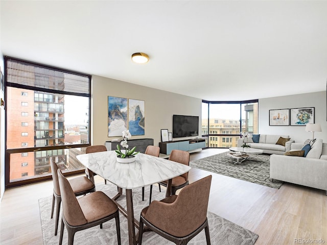 dining area with light wood-type flooring and expansive windows