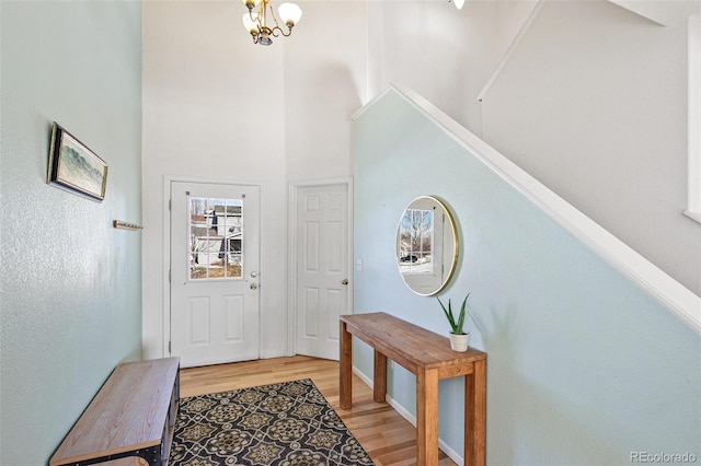 foyer with a towering ceiling, light hardwood / wood-style floors, and a notable chandelier