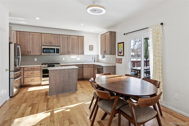 kitchen featuring appliances with stainless steel finishes, a center island, backsplash, and light hardwood / wood-style flooring