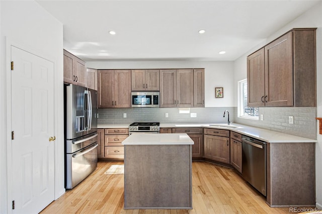 kitchen featuring sink, tasteful backsplash, a center island, stainless steel appliances, and light hardwood / wood-style floors